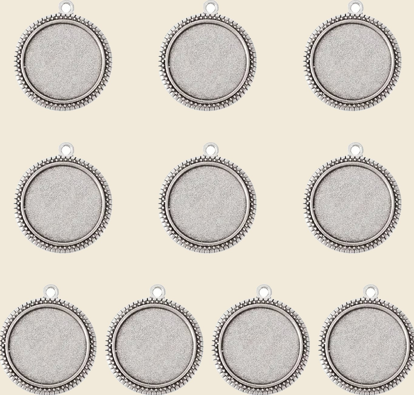 Silver-tone round bezel tray pendants on warm beige background